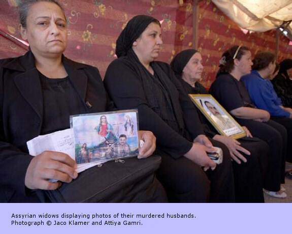 Assyrian widows displaying photos of their murdered husbands.